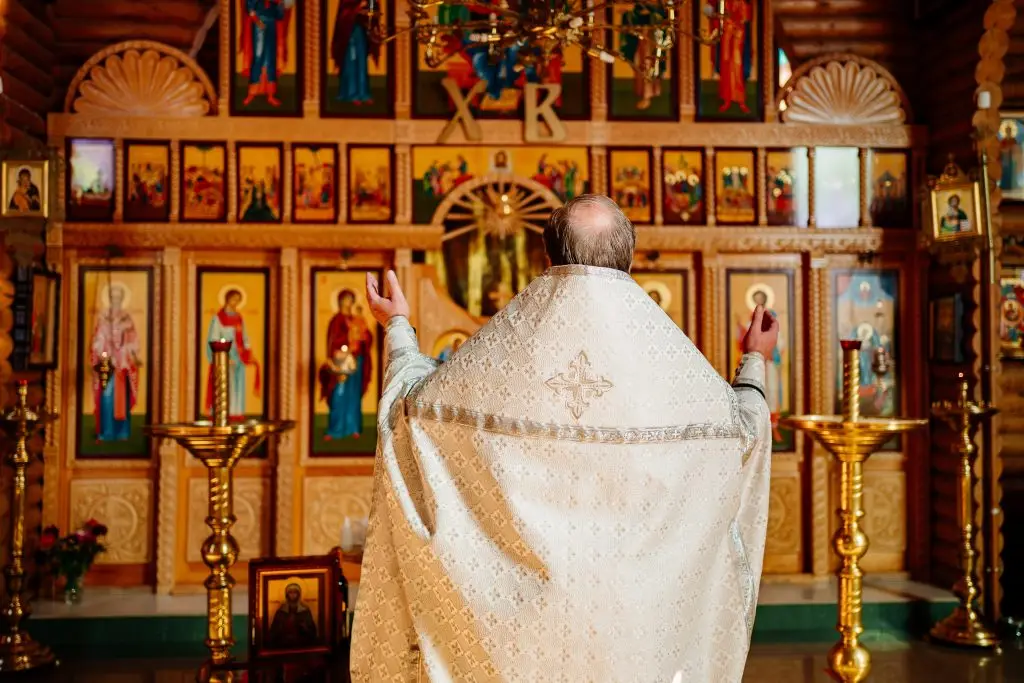 An Orthodox Christian Priest before an icon wall.